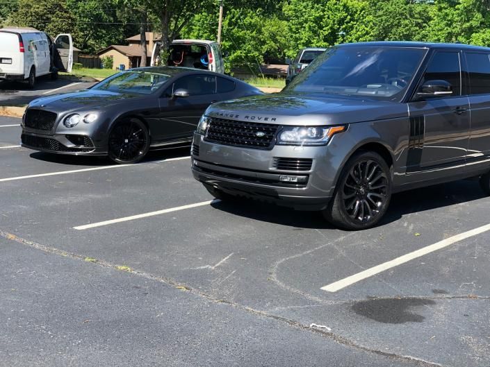 Black sports car and gray SUV parked in a lot on a sunny day
