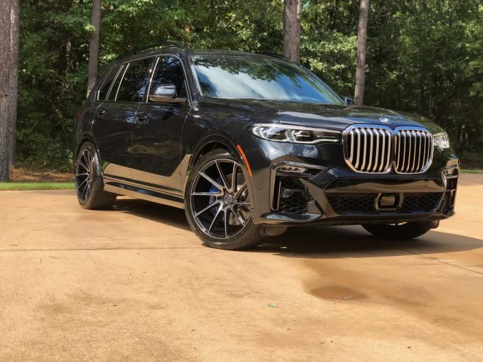 Black BMW SUV parked on a driveway with trees in the background