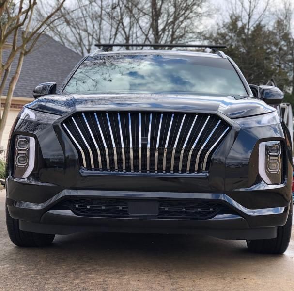 Front view of a dark gray luxury SUV with a large chrome grille, parked outdoors.