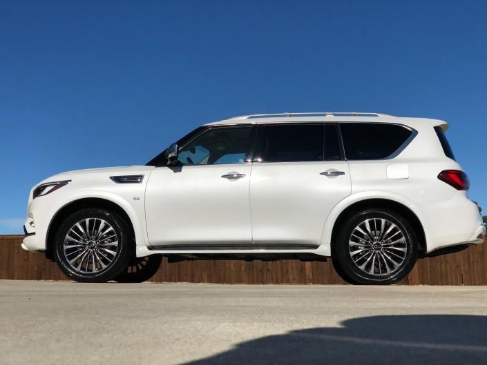 White SUV parked on a wooden barrier under a clear blue sky