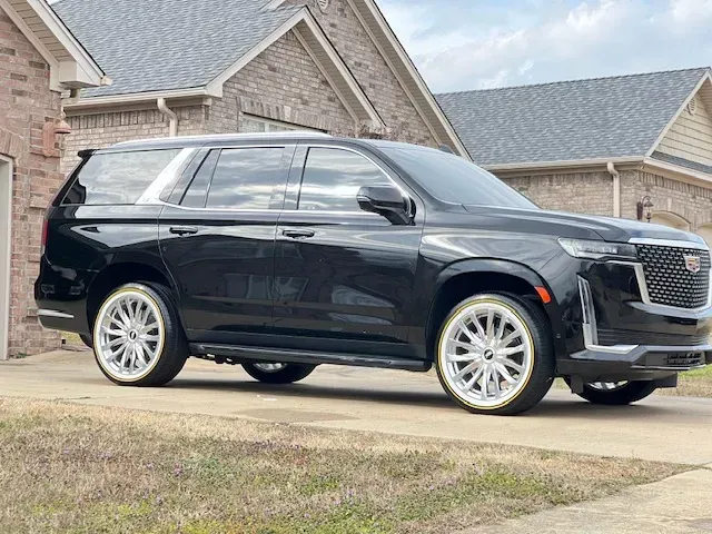 Black SUV parked in a driveway in front of a brick house