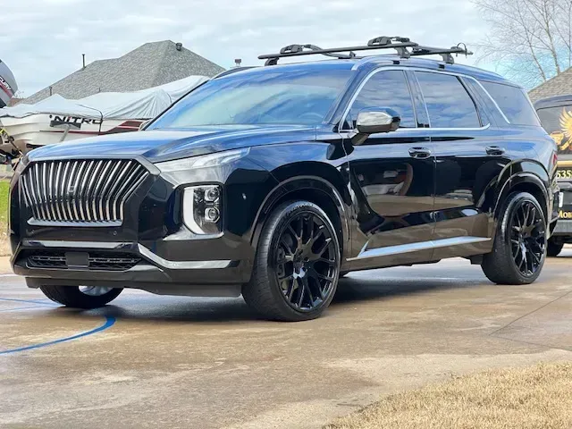 Black SUV with roof rack parked outdoors on a wet lot