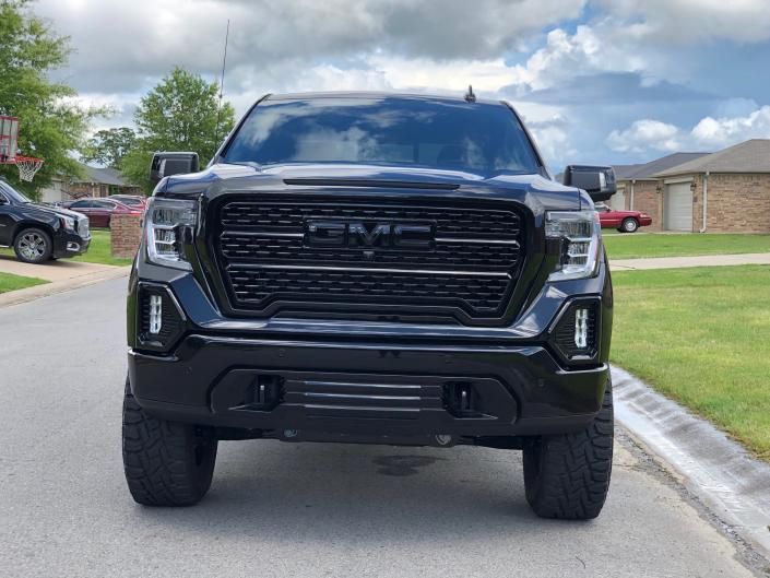 Black GMC pickup truck parked on a suburban street, front view.