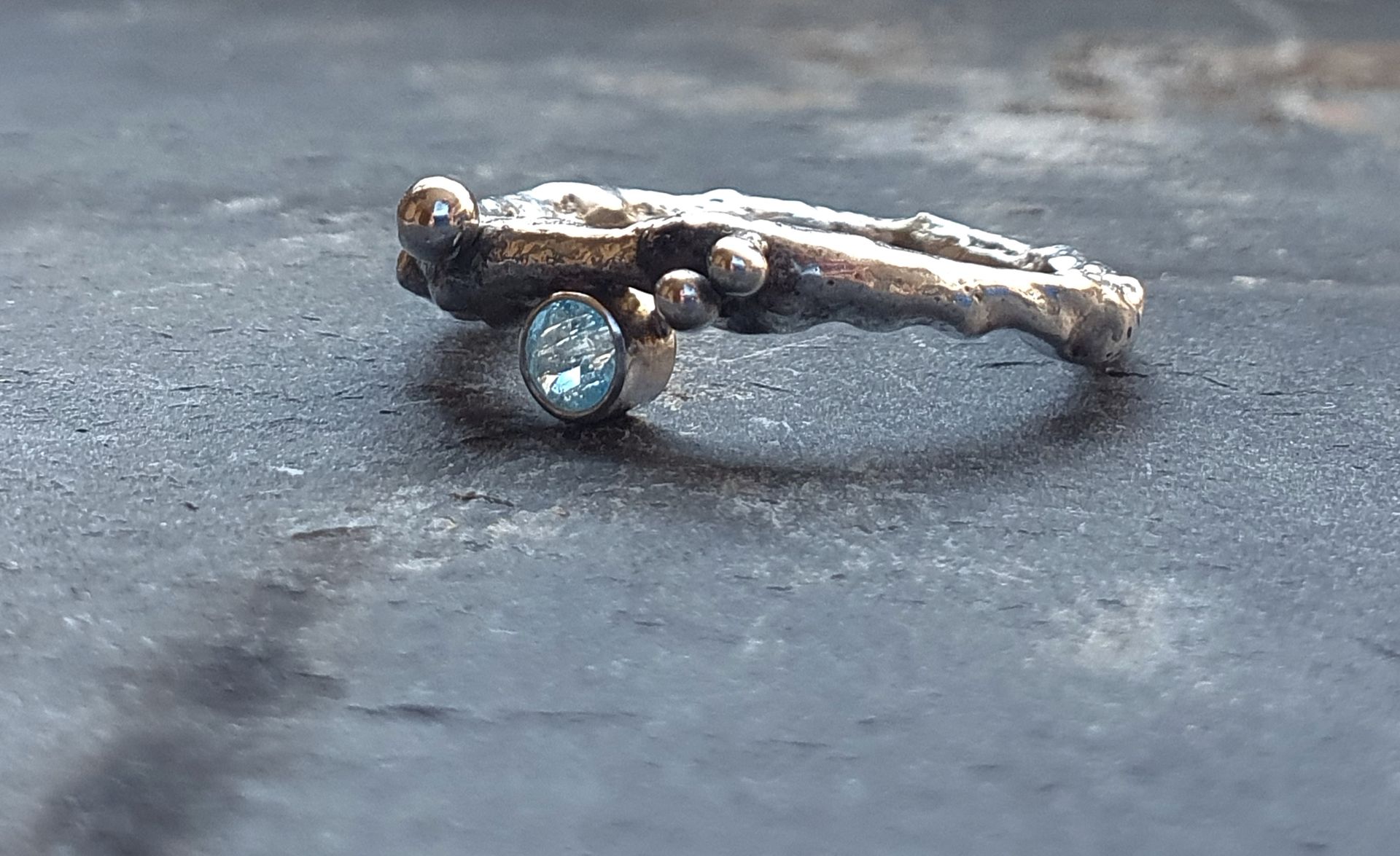 Zilveren ring met organische vorm en blauwe topaas.