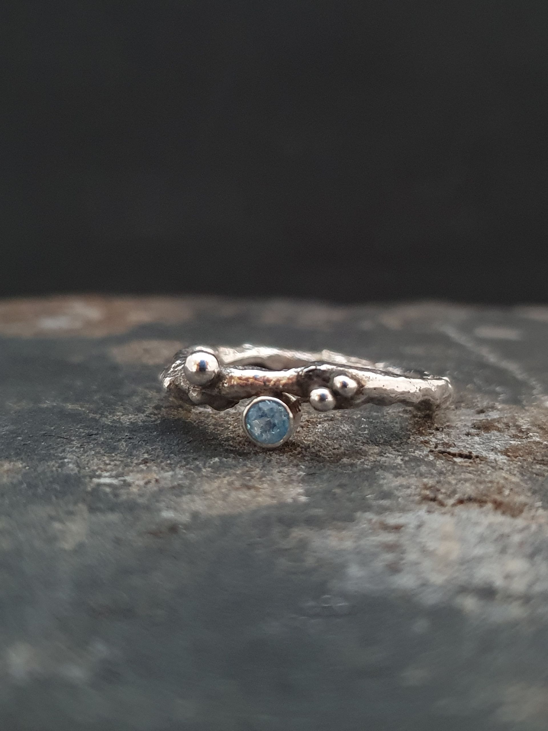 Zilveren ring met organische vorm en blauwe topaas.