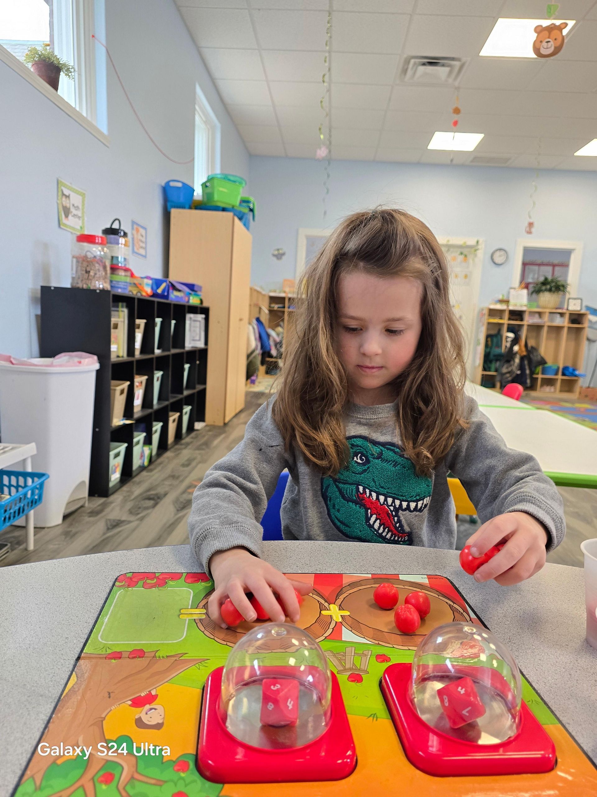 A little girl is playing with a toy in a classroom.