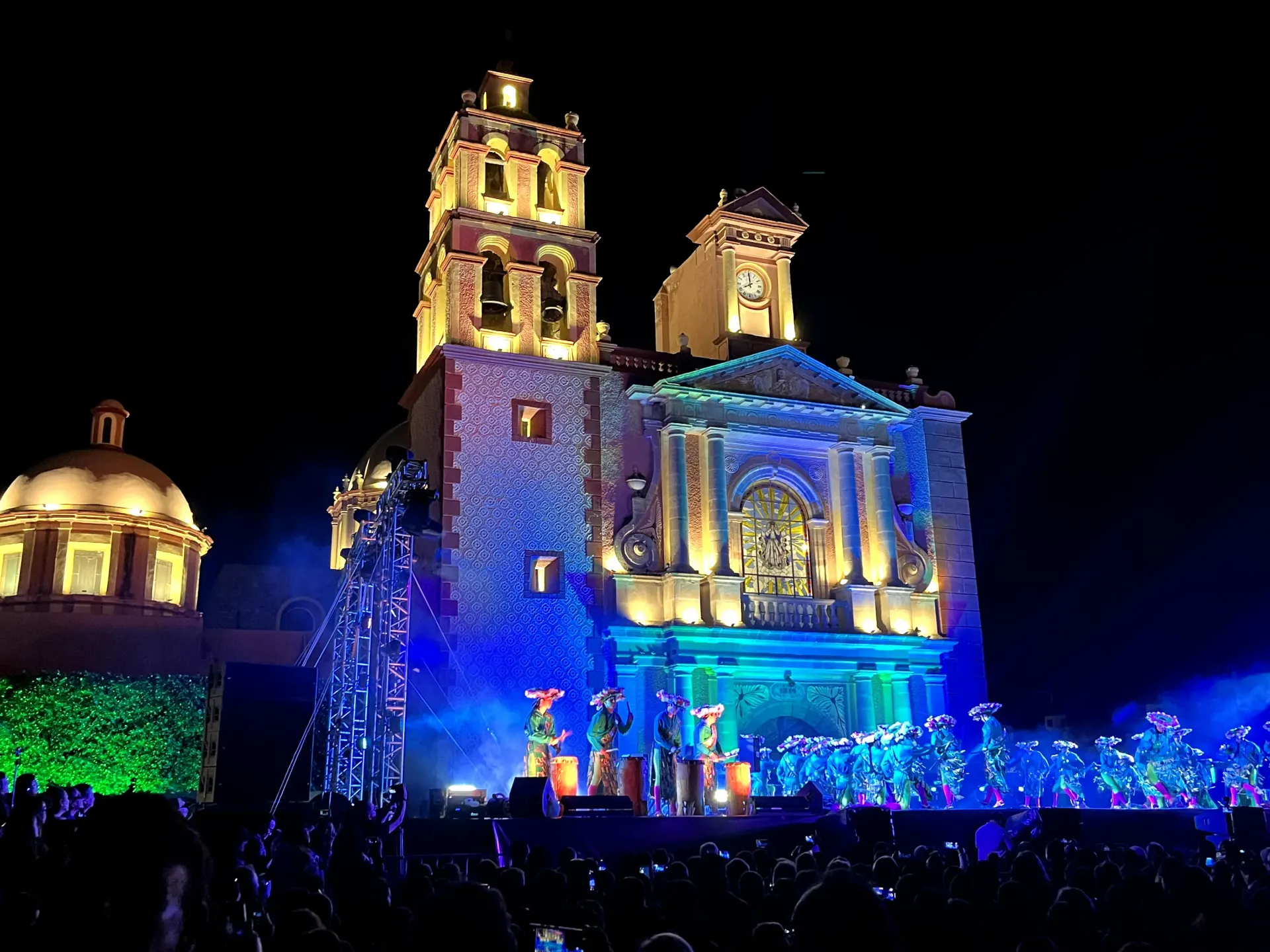Catedral iluminada de noche con luces azules y doradas contra un cielo oscuro.