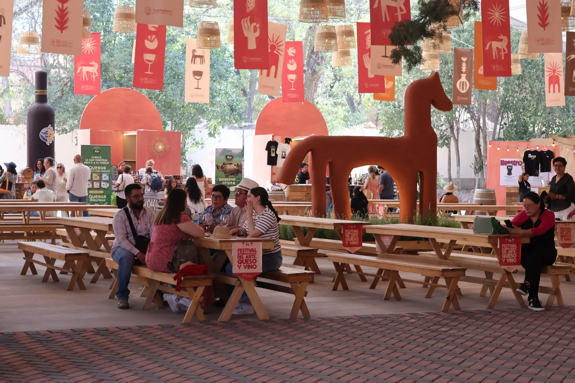 Outdoor festival with red lanterns, wooden benches, and people gathered in a decorated courtyard.