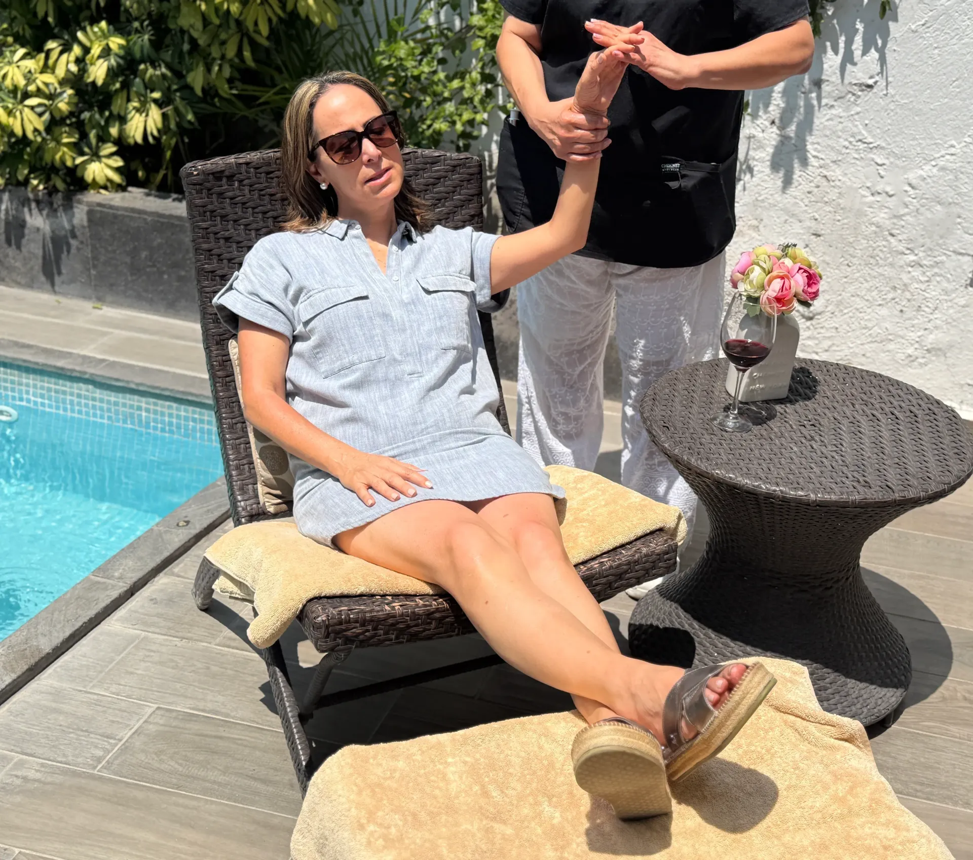 persona está recostada junto a la piscina, tomada de la mano de alguien que está de pie cerca, al lado de una piscina.