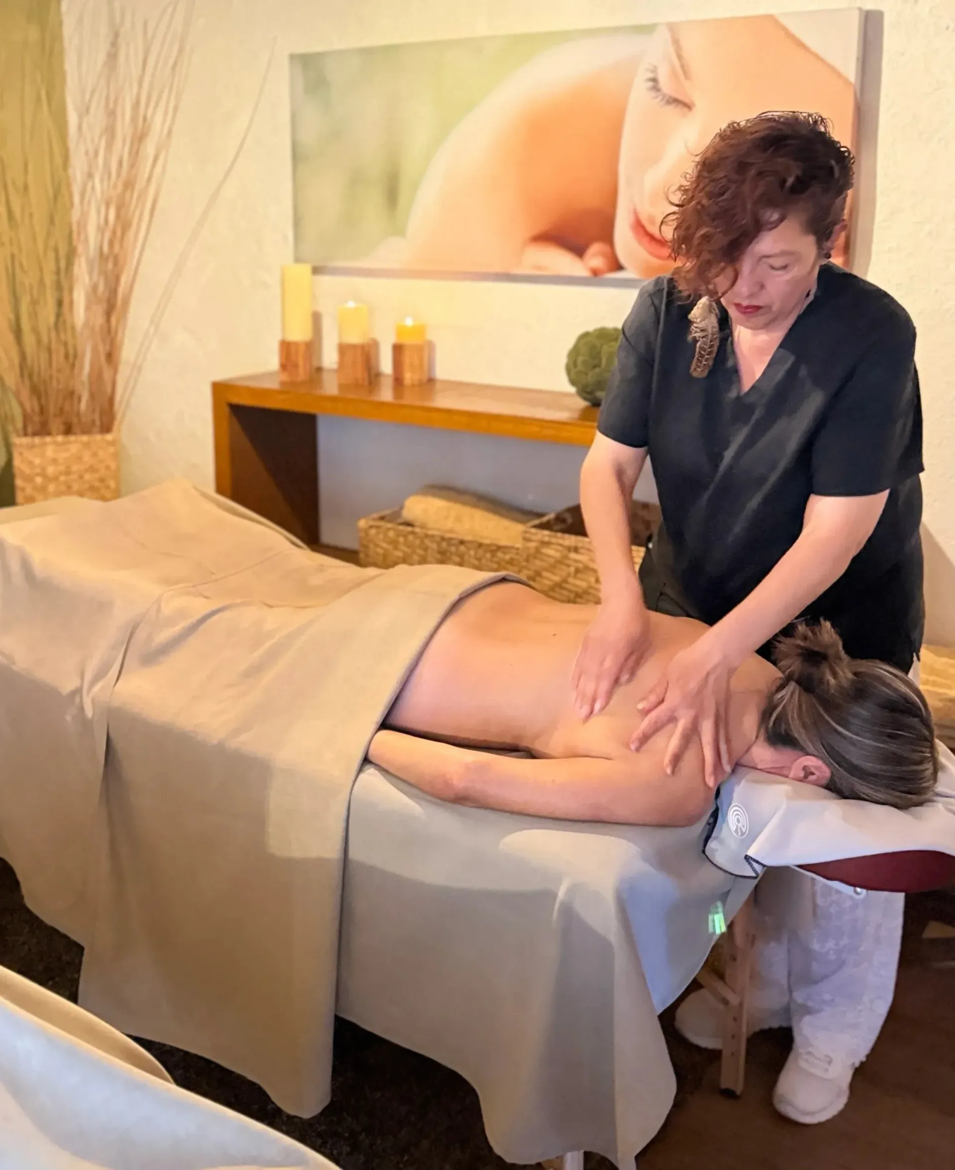 Masajista trabajando en un cliente en una camilla de masaje en una tranquila sala de spa.