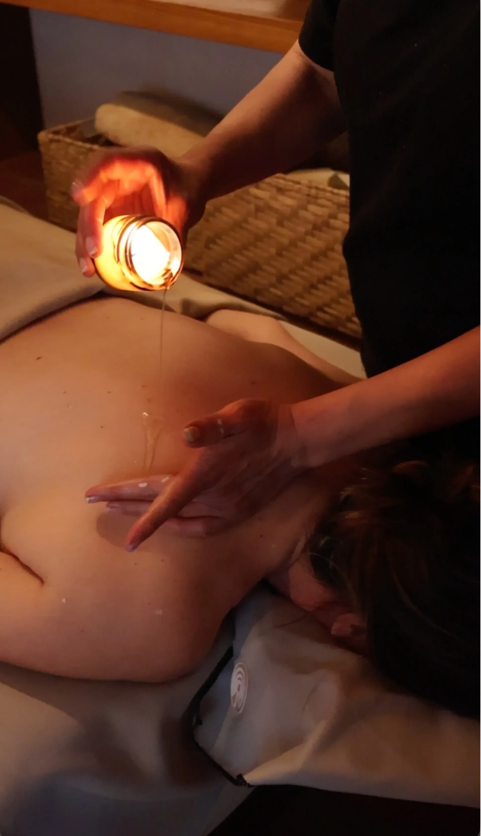 Persona que realiza una terapia de ventosas en la espalda de otra persona, con una ventosa caliente al rojo vivo.