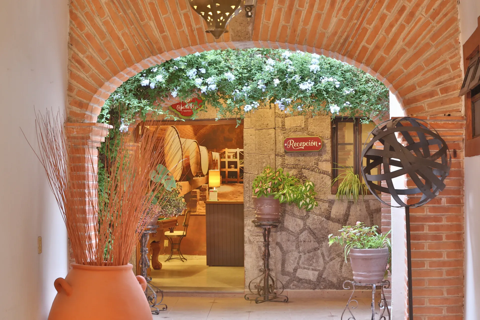 Brick-arched courtyard entrance with plants, a stone wall, and warm café-style decor inside