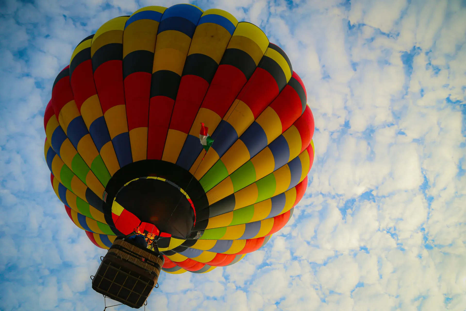Globo aerostático colorido visto desde abajo contra un cielo azul nublado