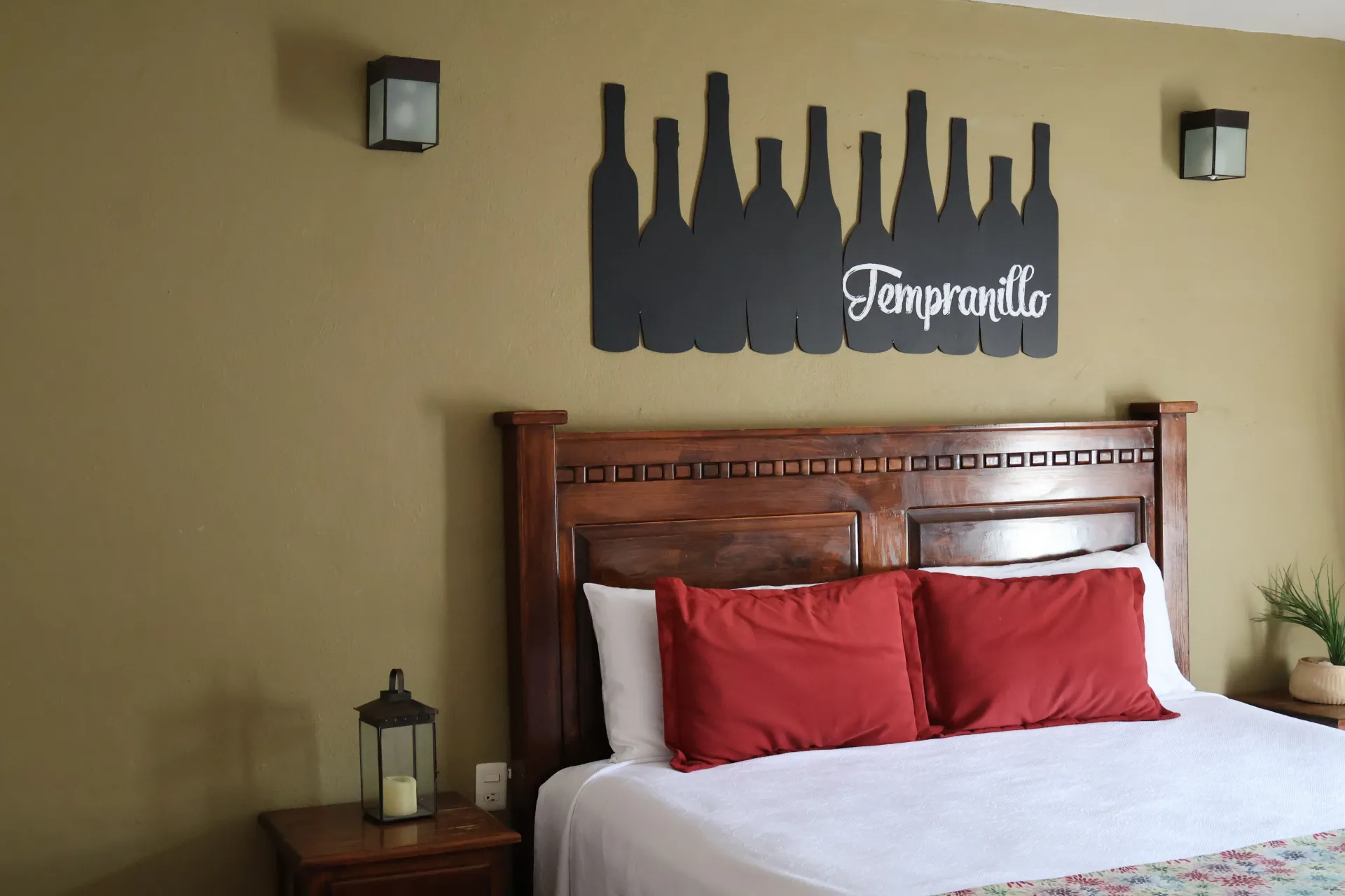 Bedroom with wooden bed, white bedding, red pillows, and a wall sign reading “Teresita.”