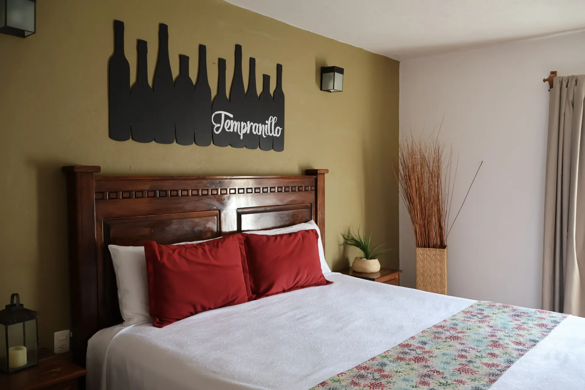 Bedroom with wooden bed, red pillows, city skyline wall art, and soft neutral decor