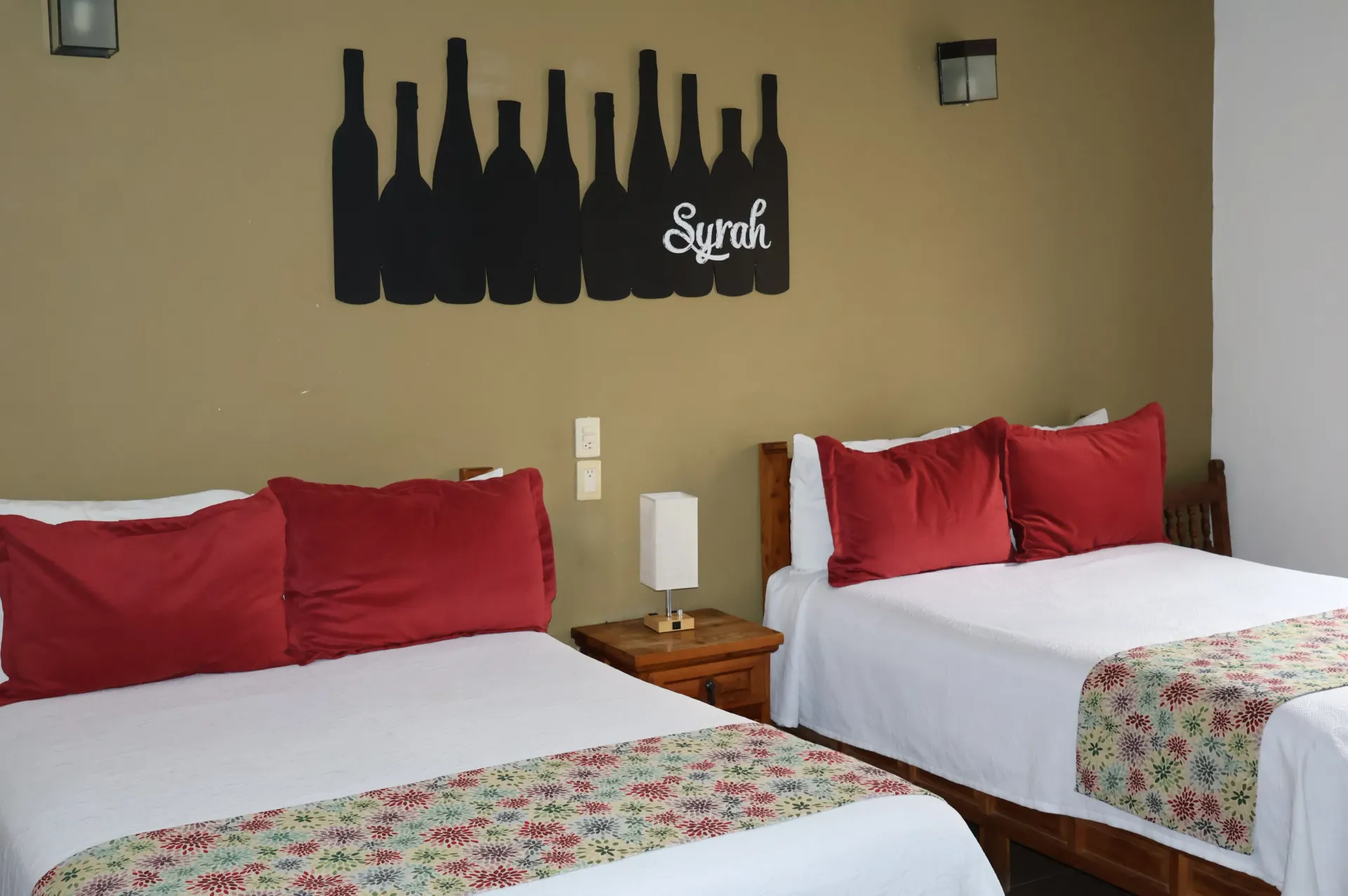 Hotel room with two beds, red pillows, and a wall art silhouette above the headboards
