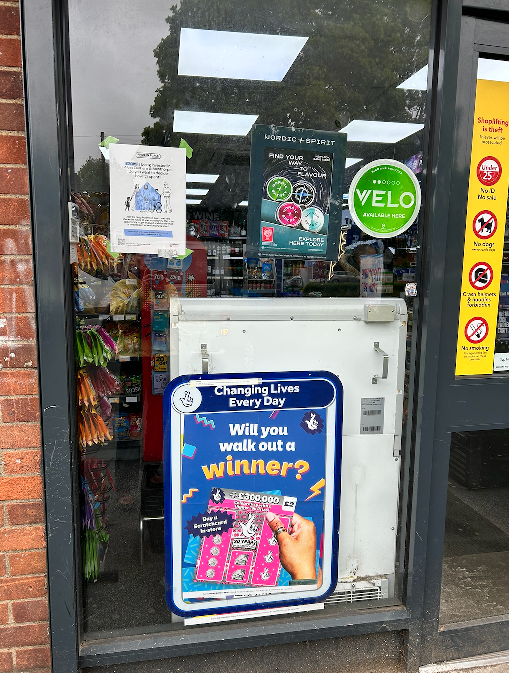 Store entrance with a colorful “Can you win this winner?” sign and VELO sticker on the glass door.