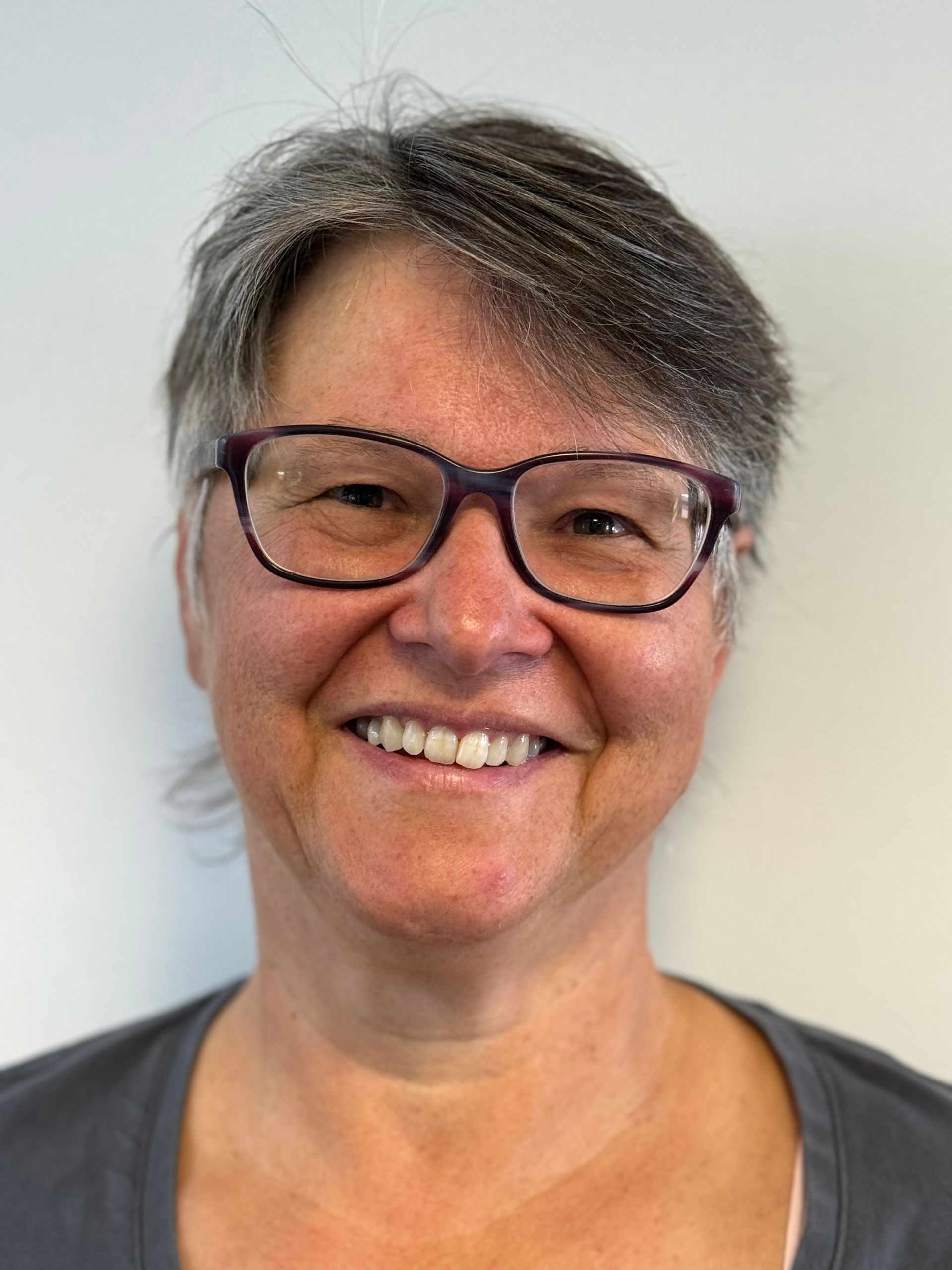 Eine Frau mit Brille lächelt in die Kamera.