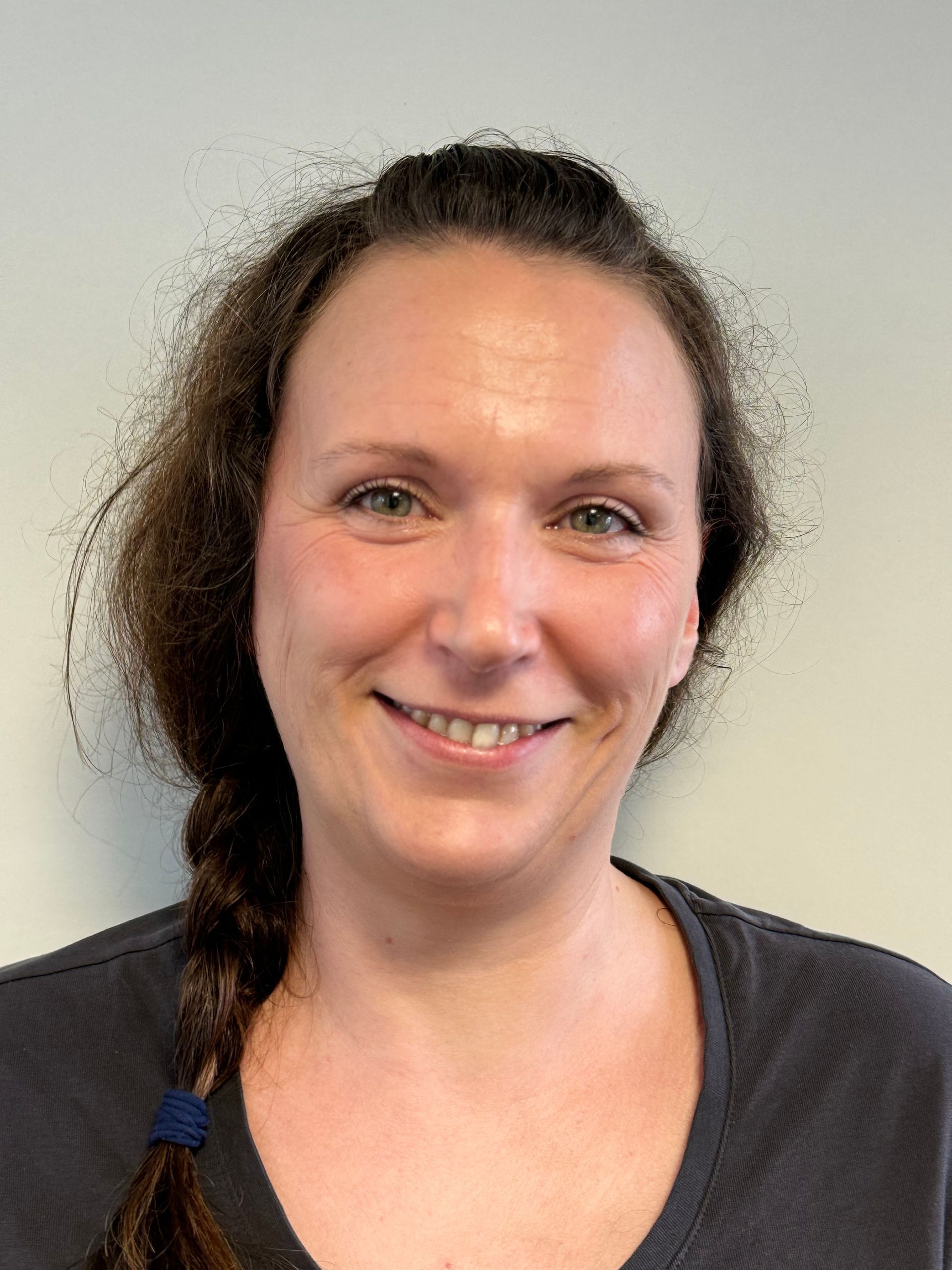 Eine Frau mit einem Zopf im Haar lächelt in die Kamera.