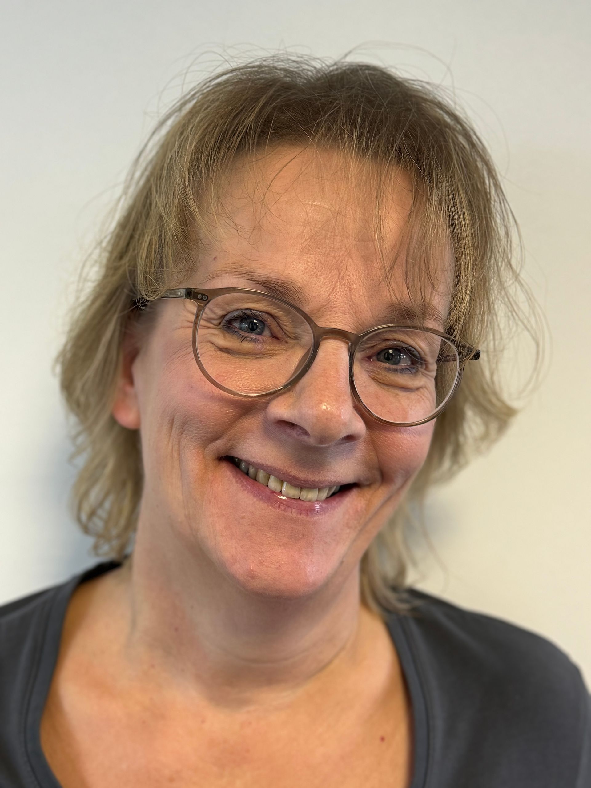 Eine Frau mit Brille lächelt in die Kamera.