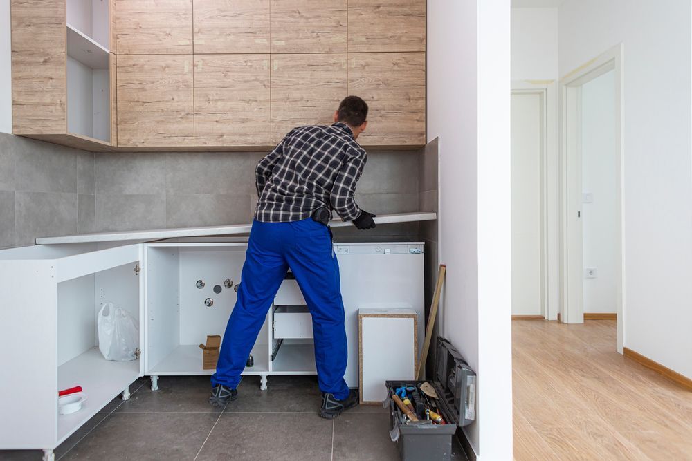 A Man In Blue Pants Is Working On A Kitchen — Damn Fine Constructions In Nambucca Heads, NSW
