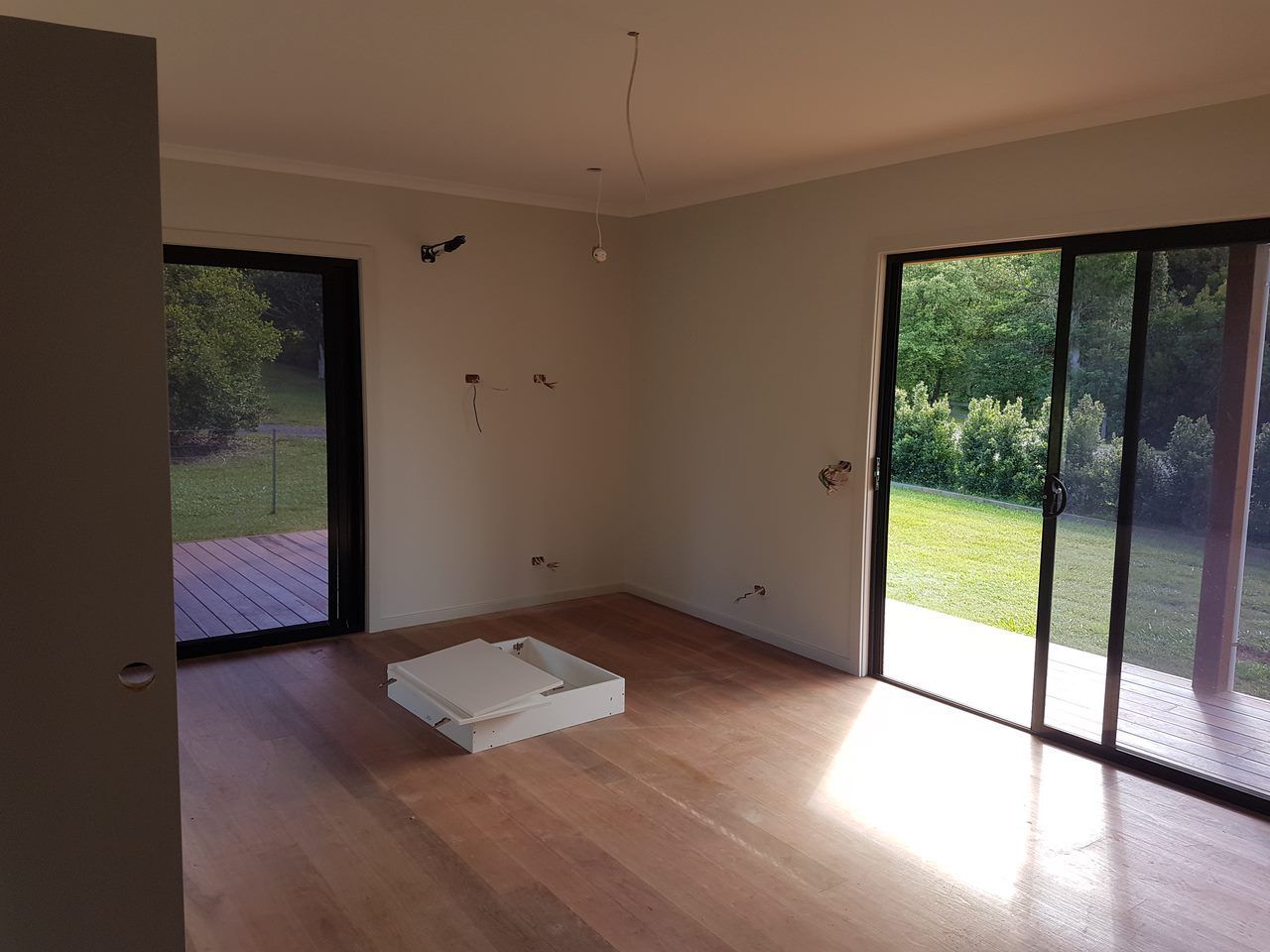 An Empty Room With Hardwood Floors And Sliding Glass Doors — Damn Fine Constructions In Nambucca Heads, NSW