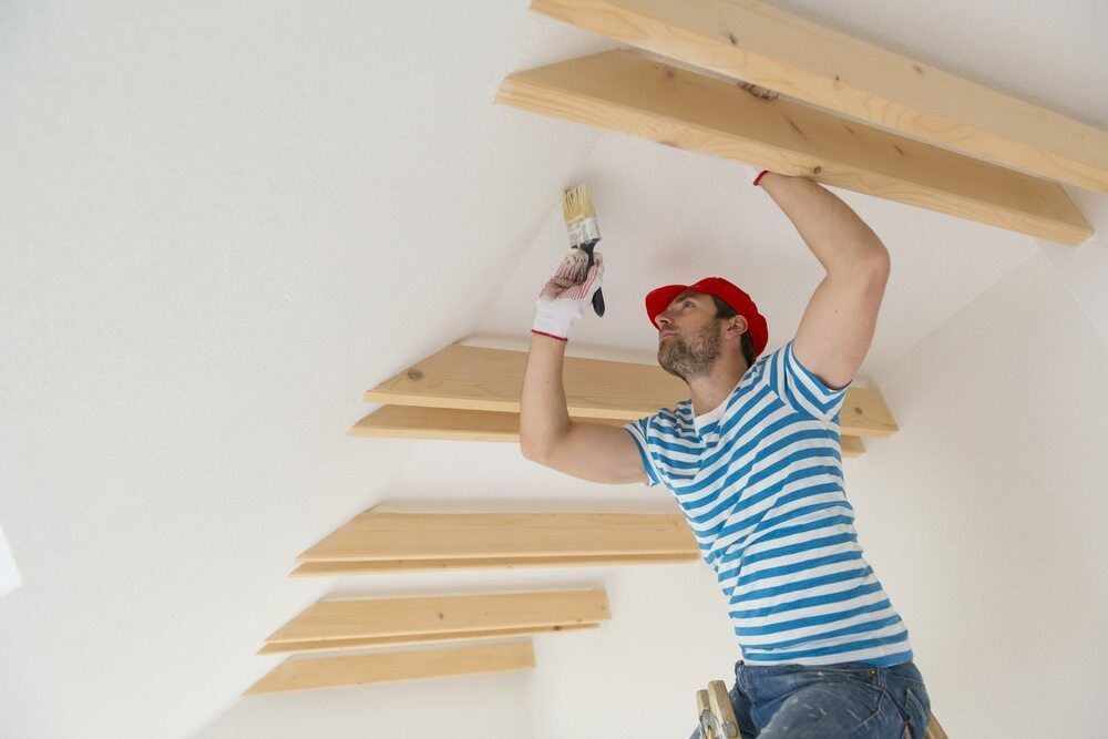 A Man Is Painting A Ceiling With A Brush — Damn Fine Constructions In Bellingen, NSW