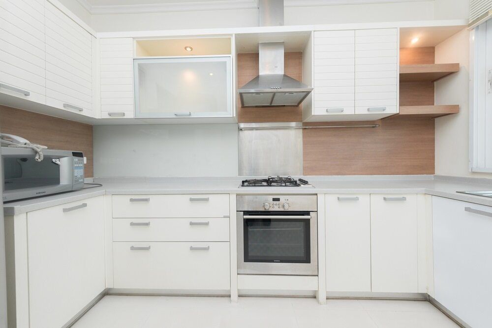 A Kitchen With White Cabinets And Stainless Steel Appliances — Damn Fine Constructions In Nambucca Heads, NSW