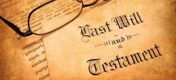 Close-up of a last will and testament document beside eyeglasses on a sepia-toned desk