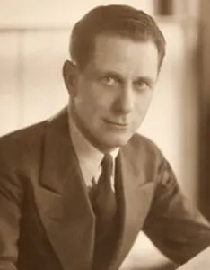 Sepia portrait of a Harry Benoit in a suit, seated and looking toward the camera.