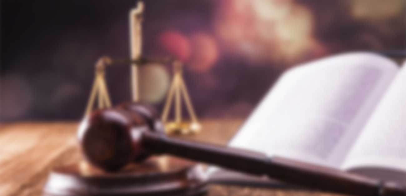 Law books and a gavel beside scales of justice on a desk