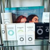 NUFRAFOL product display with white and black boxes, bottles, and a teal promotional poster on a shelf