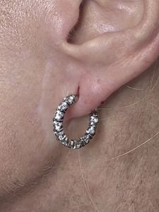 Close-up of an ear wearing a silver hoop earring with small clear stones