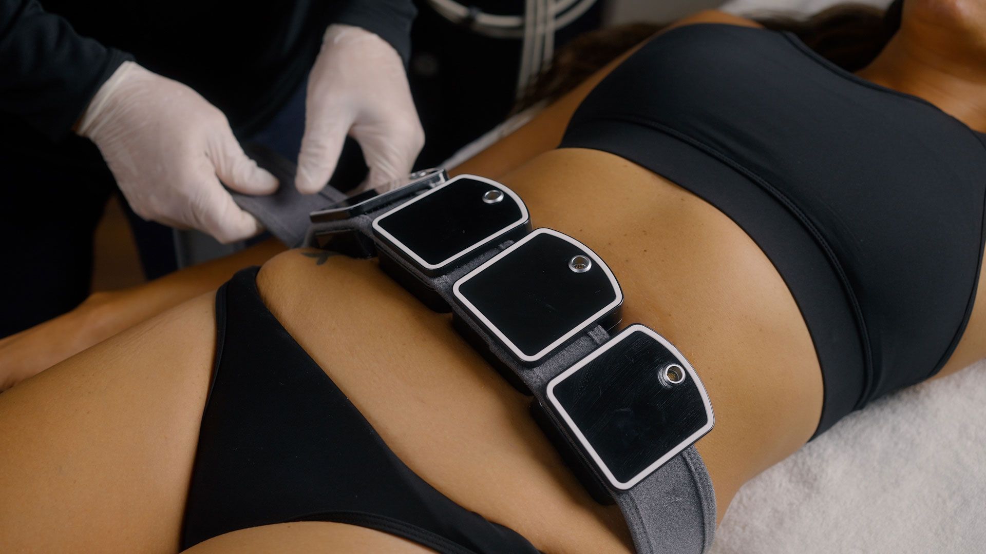 Handheld massage device gliding over a person’s bare back on a spa treatment table