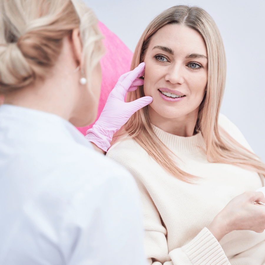 Cosmetic consultation with a practitioner examining a woman’s face in a bright clinic