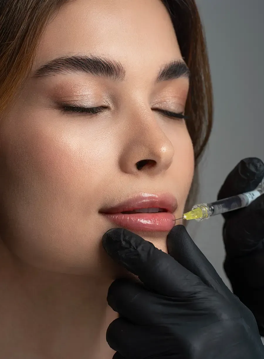 Close-up of a woman receiving lip filler injection from a gloved practitioner