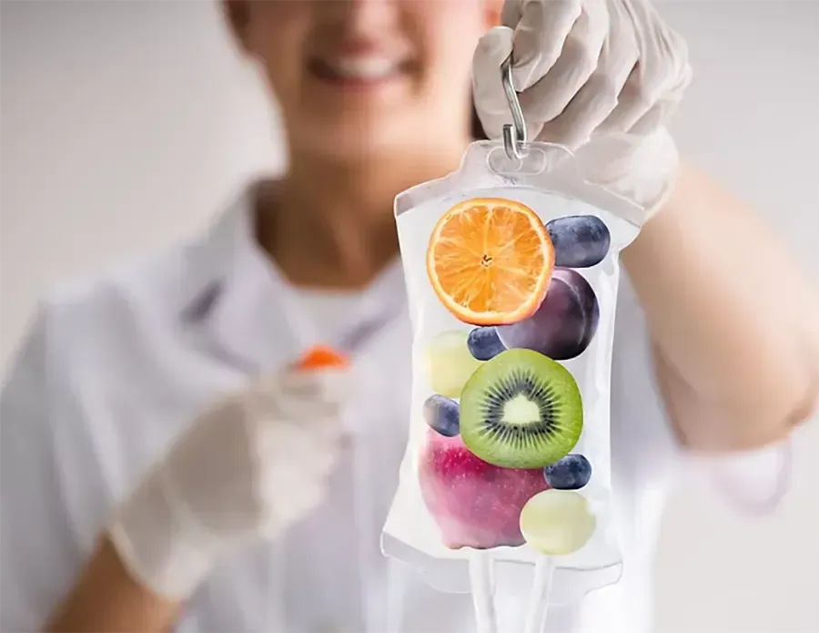 Gloved person holding a clear infusion bag filled with colorful fruit slices and berries