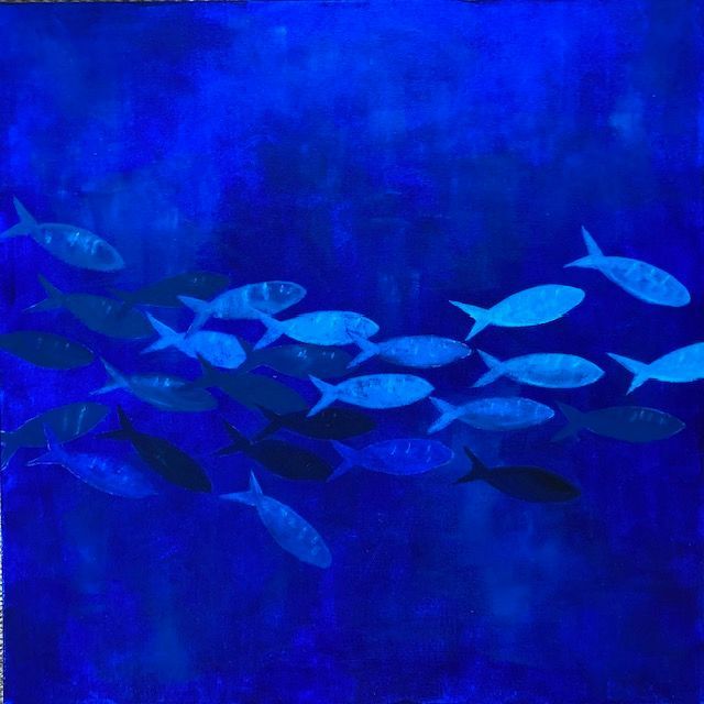 School of silver fish swimming in deep blue water