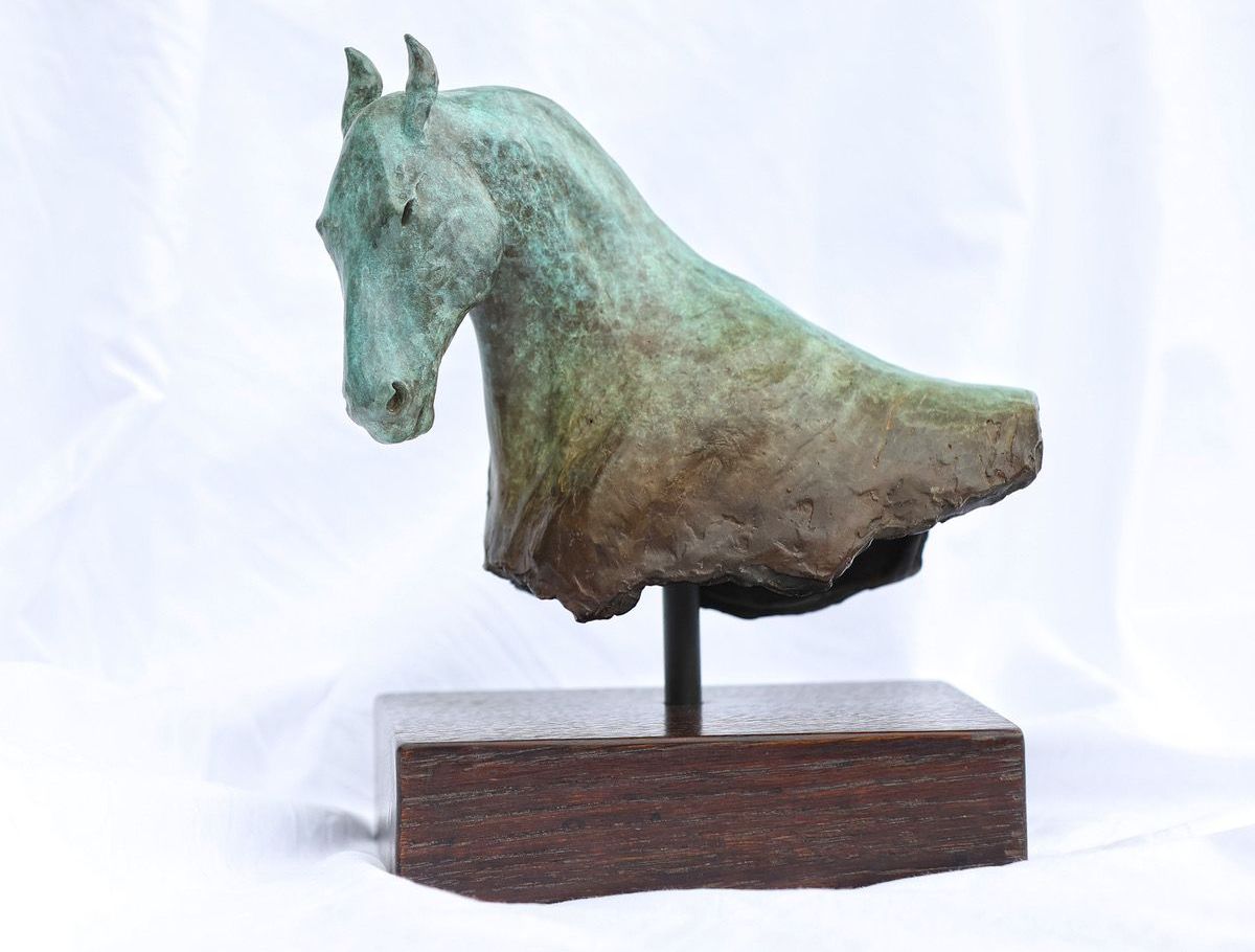 Bronze horse bust sculpture on a dark wooden base against a white background