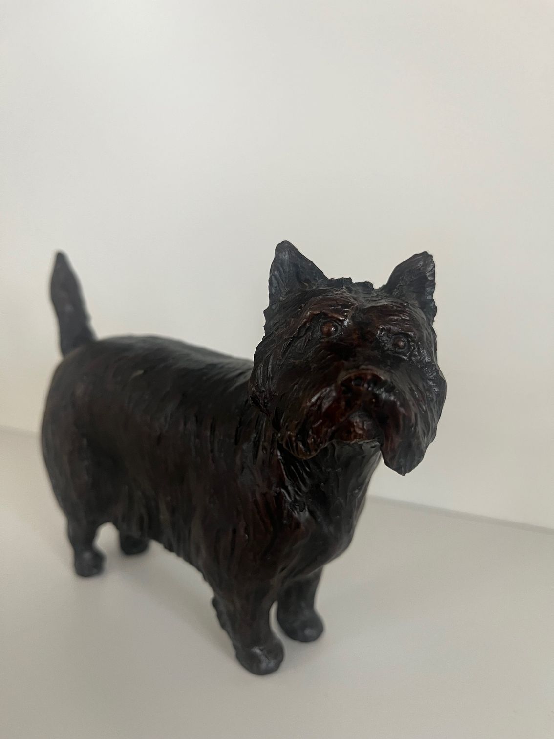Black figurine of a Westie Terrier dog standing on a white surface.