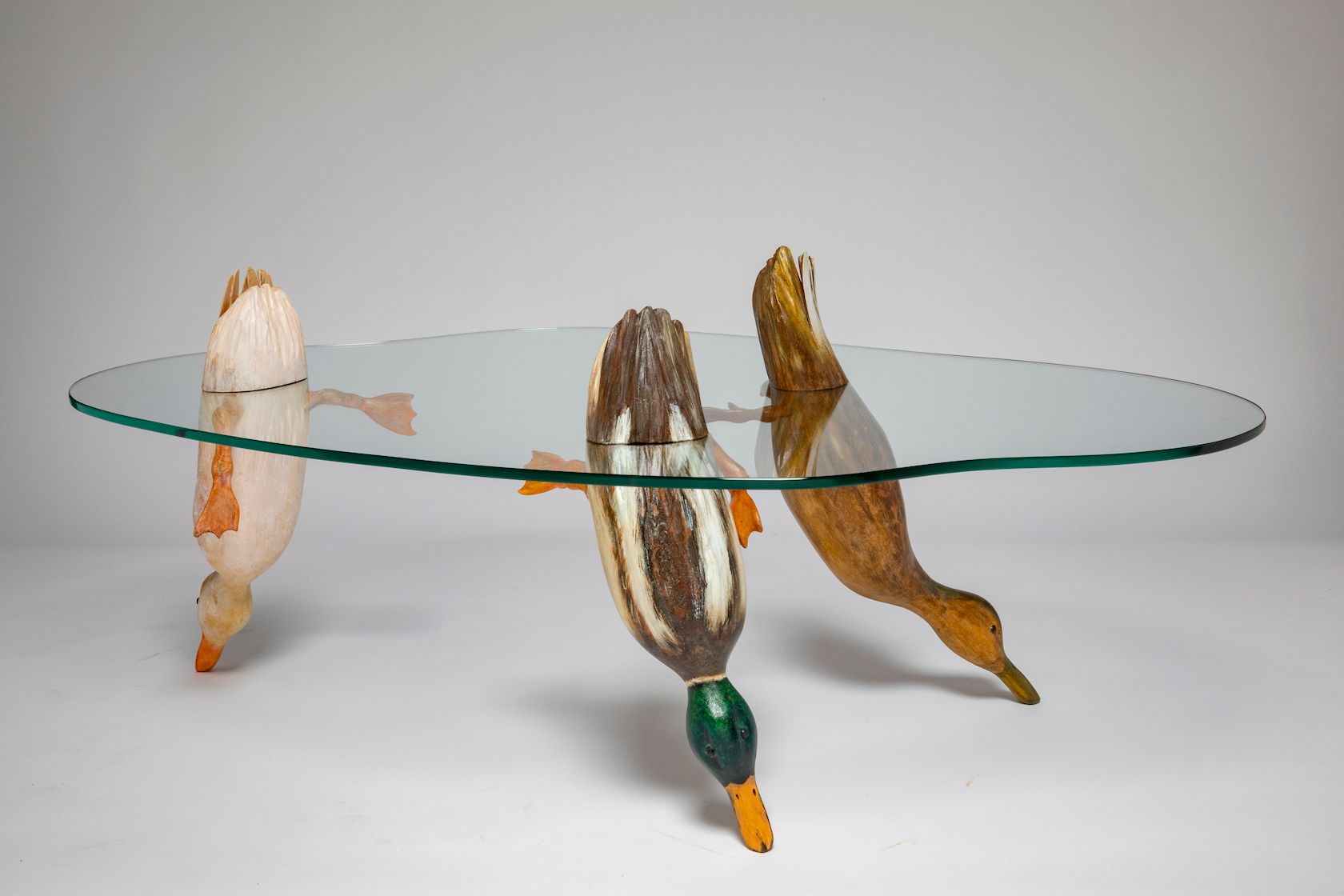 Glass tabletop on sculptural bird-shaped bases with colorful accents
