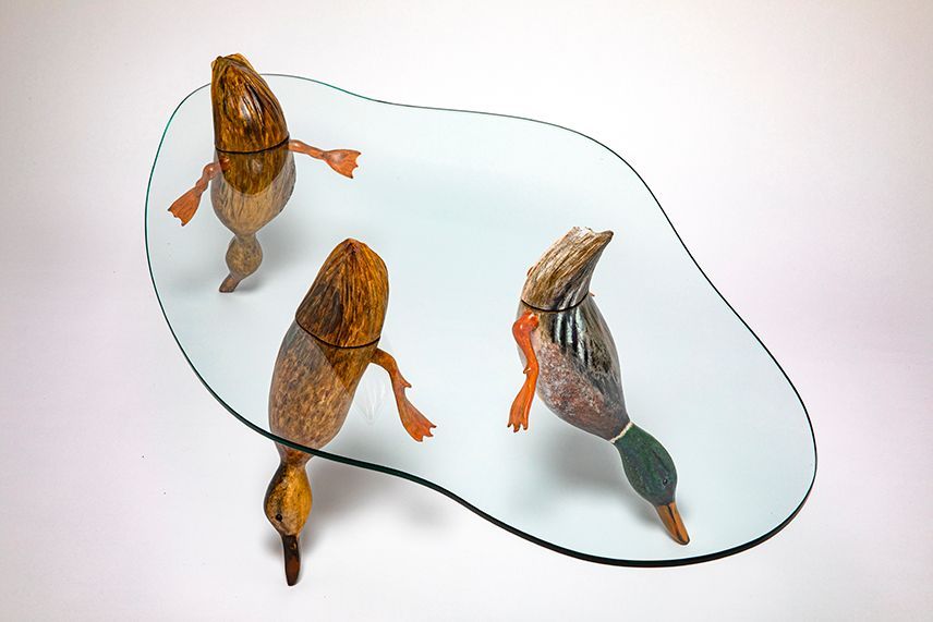 Three orange-and-gray duck-shaped figurines on a white surface, outlined by a black contour line