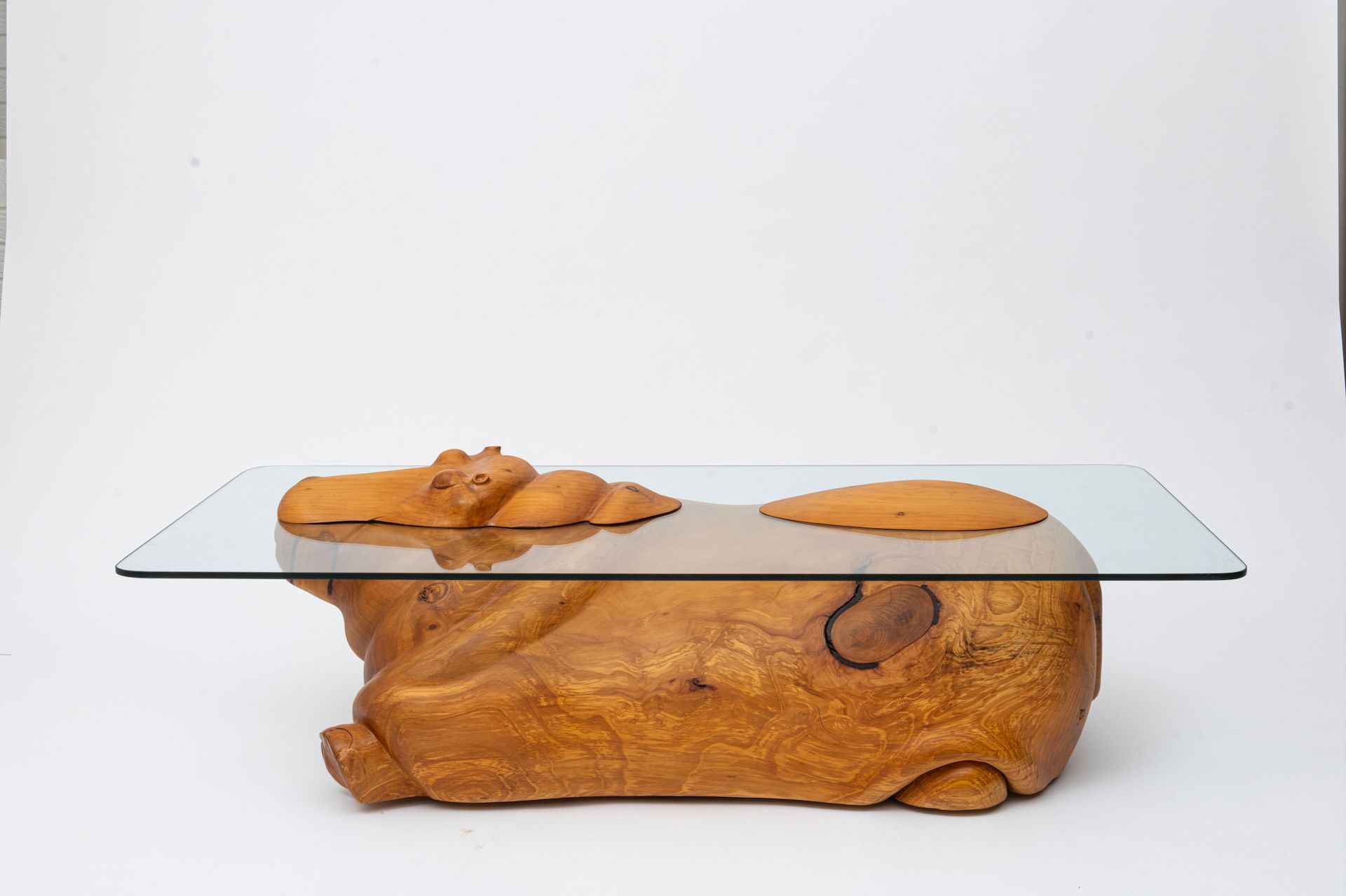 Glass tabletop on a carved wooden base with two small wooden sculptures on top