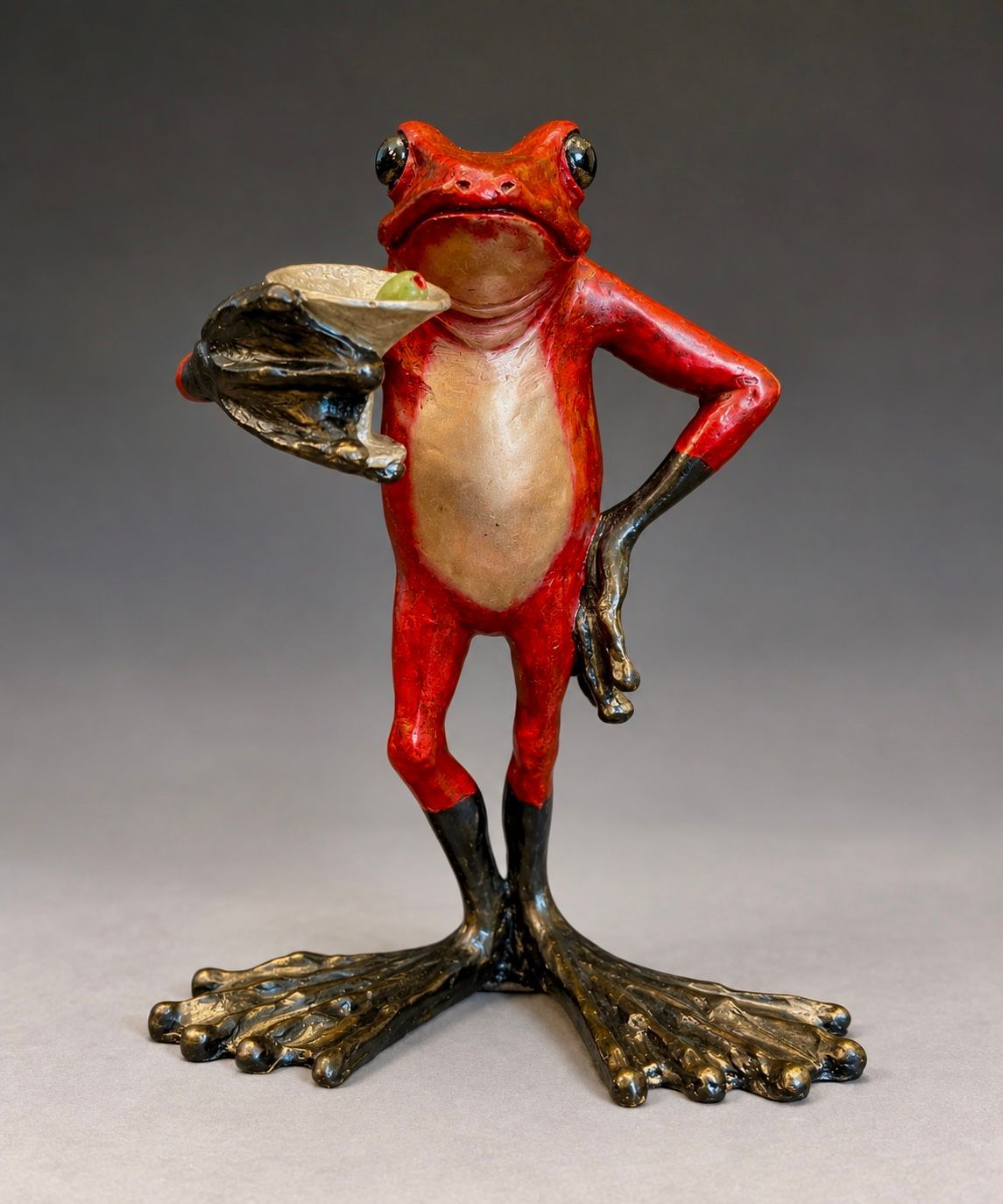 Red frog figurine with black legs and gold feet, standing upright with one hand on its hip.