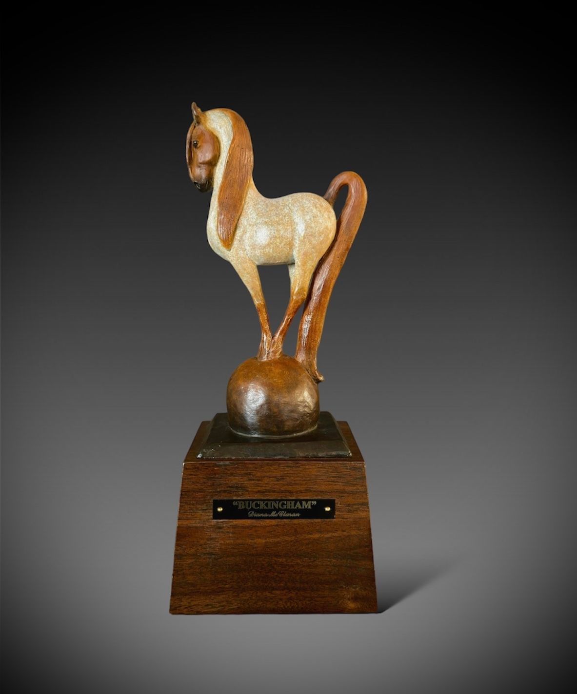 Horse statue on wooden base; tan and white, balanced on sphere; trophy.
