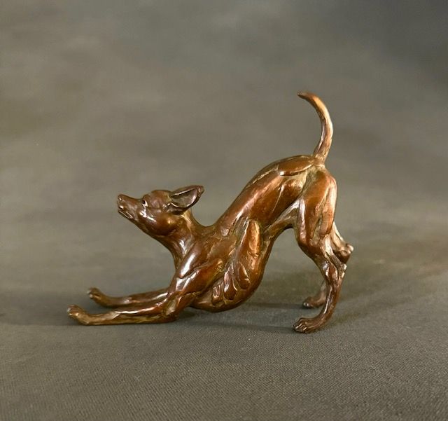 A bronze statue of a dog stretching its legs