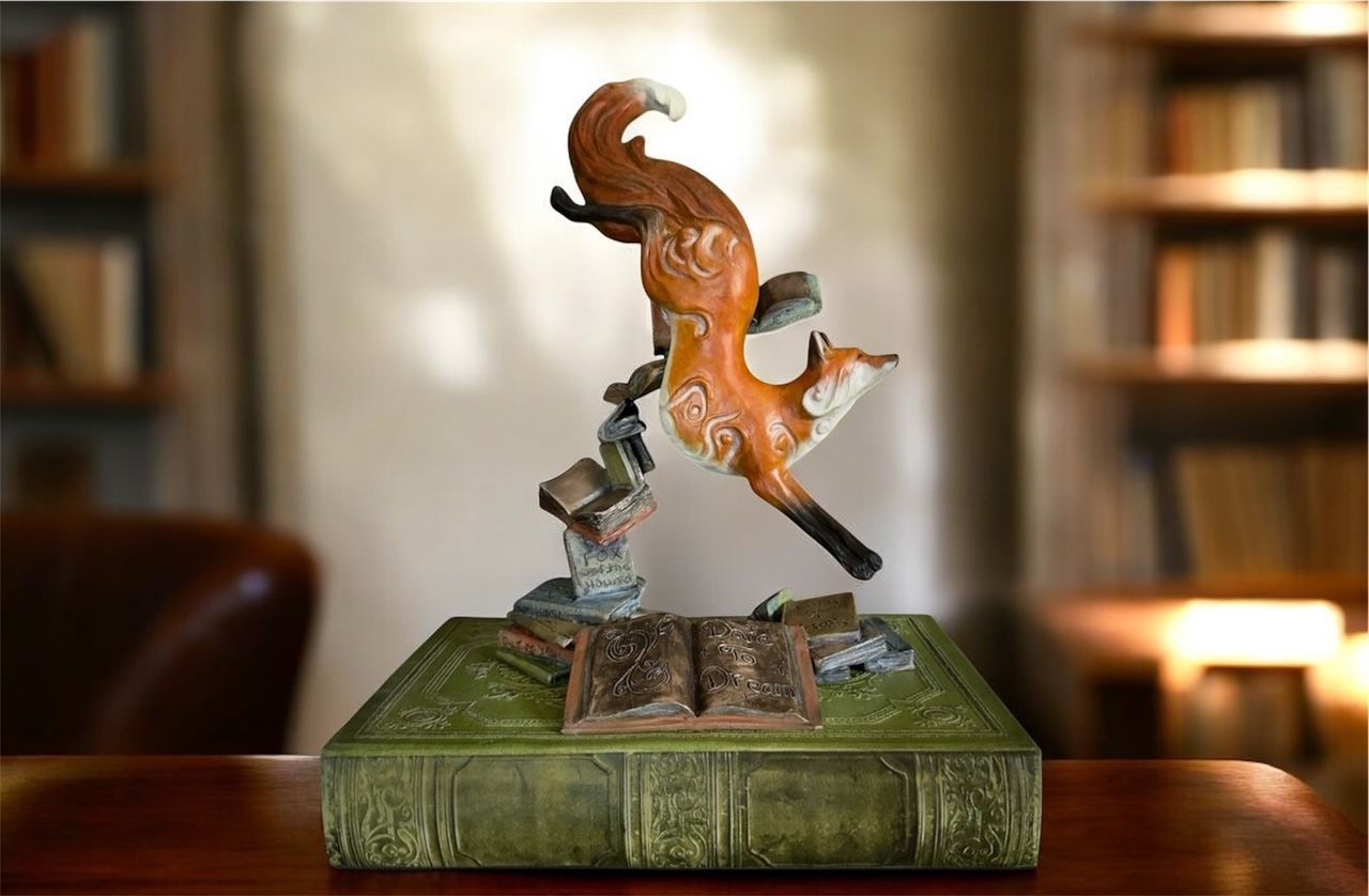 Orange fox sculpture leaping from an open book on a green pedestal, with a small metallic figure beneath it