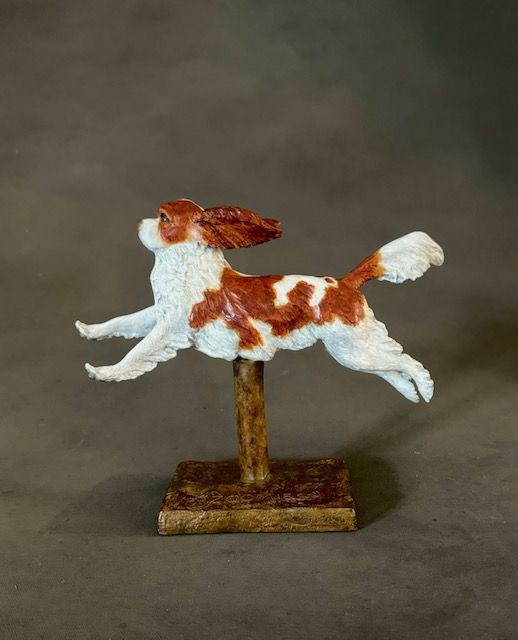 A statue of a brown and white dog jumping in the air