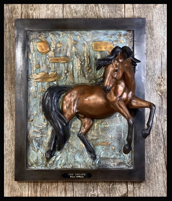 Bronze horse sculpture in a dark frame against a textured beige background.