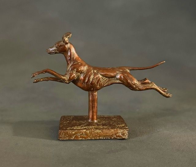 A bronze statue of a greyhound running on a pedestal.